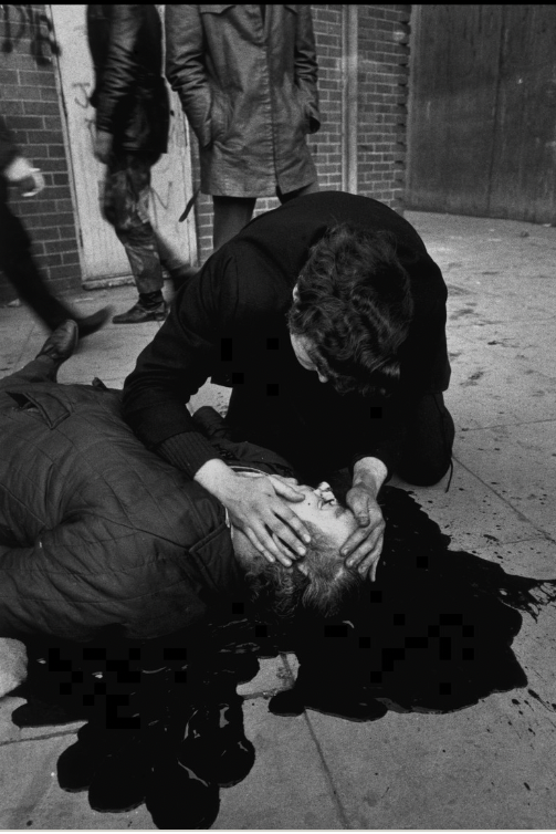 Gilles Peress (French) As the shooting stops on Bloody Sunday a victim lies dead, Derry, 1972